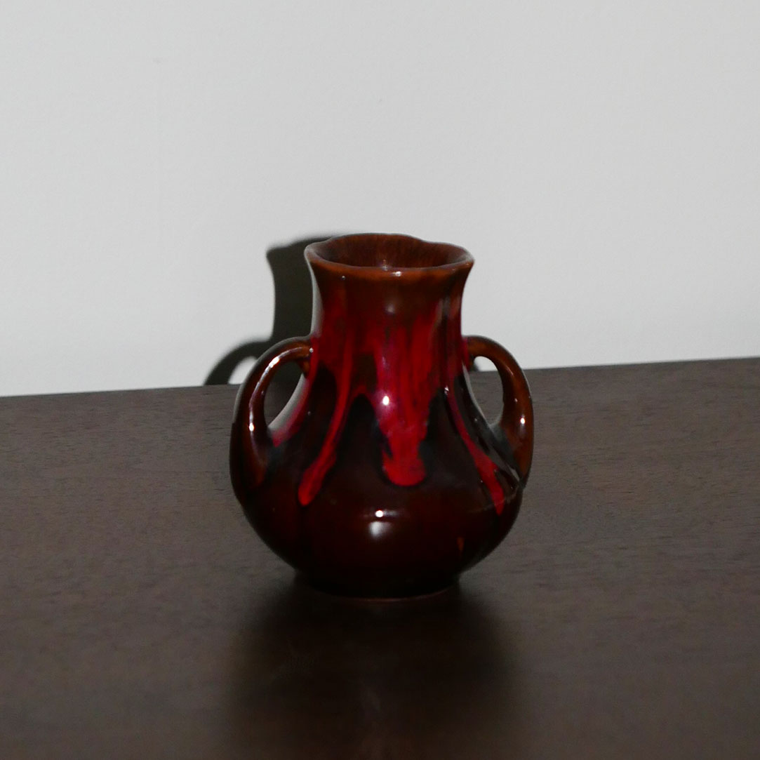 small mcm vase with handles featuring drip glaze design in warm red and brown tones.