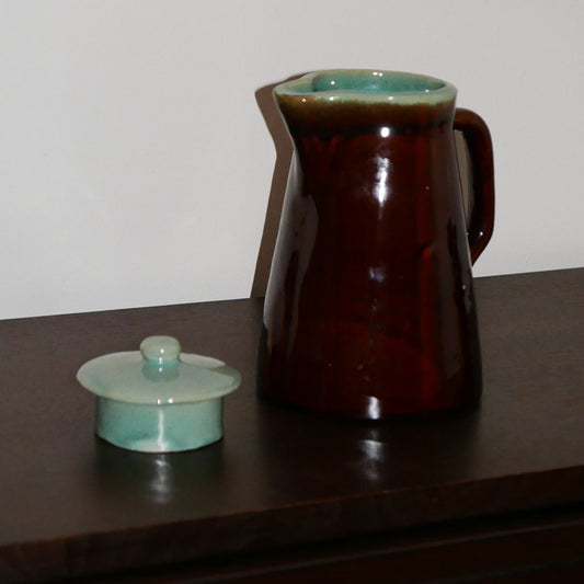 mid-century pitcher in brown & teal featuring glazed finish, handle, lid, and round base.